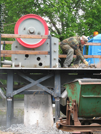 Das gebrochene Gestein fällt unten aus dem Brecher und wird per Hand ...